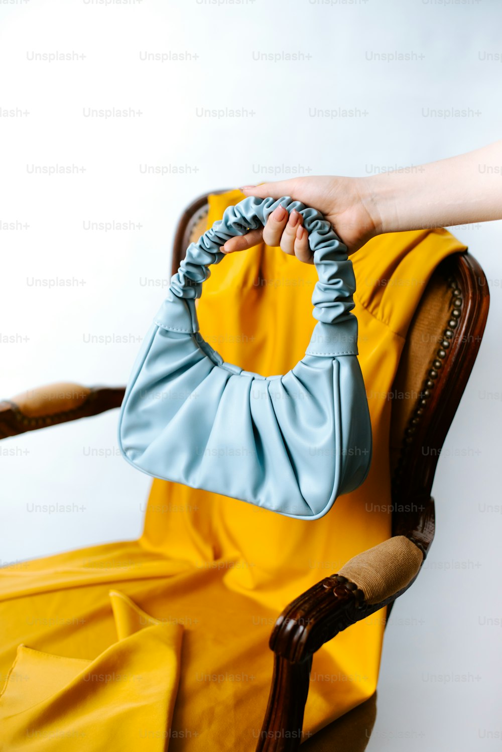 a woman's hand holding a purse on a chair