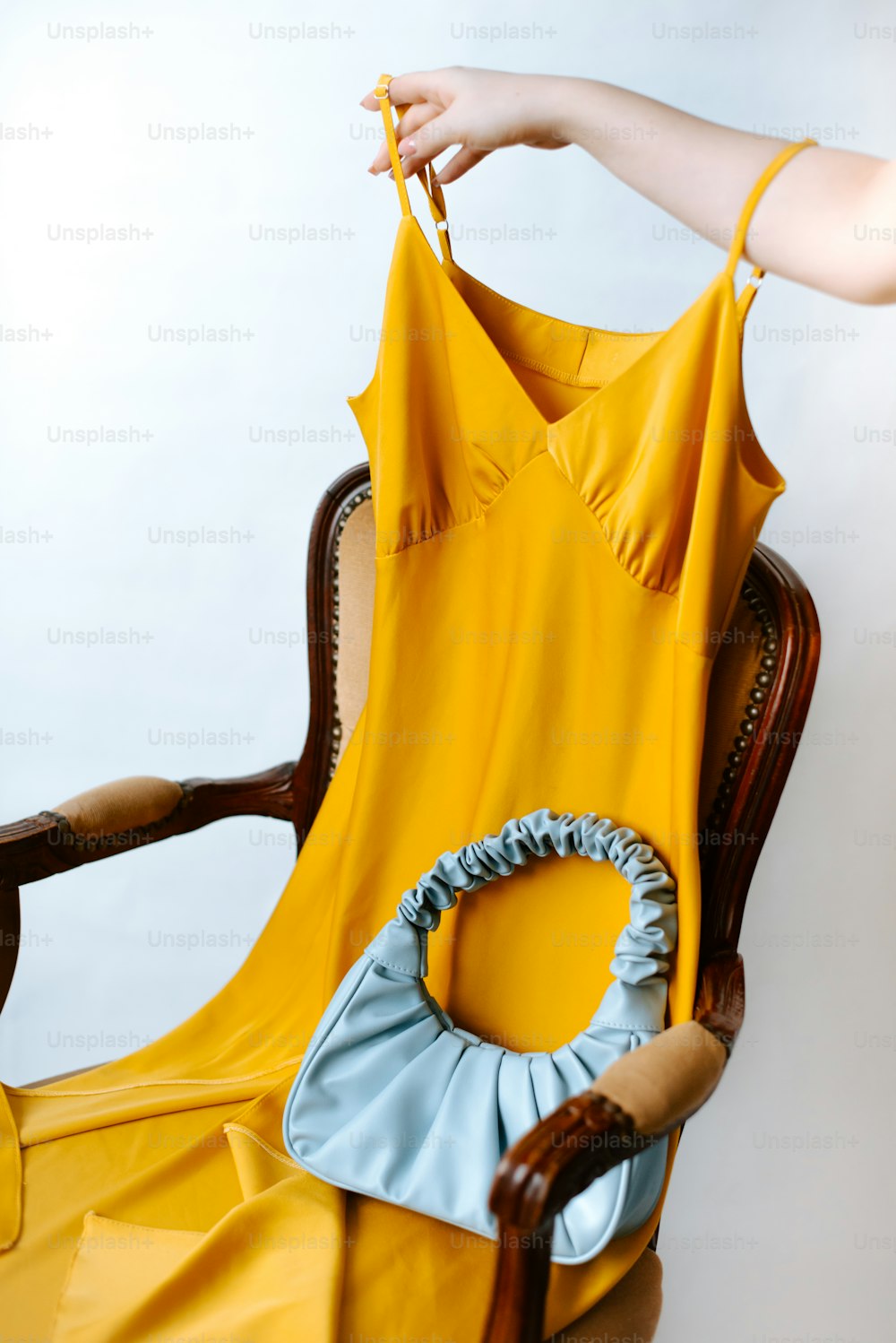 a woman is holding a yellow dress on a chair