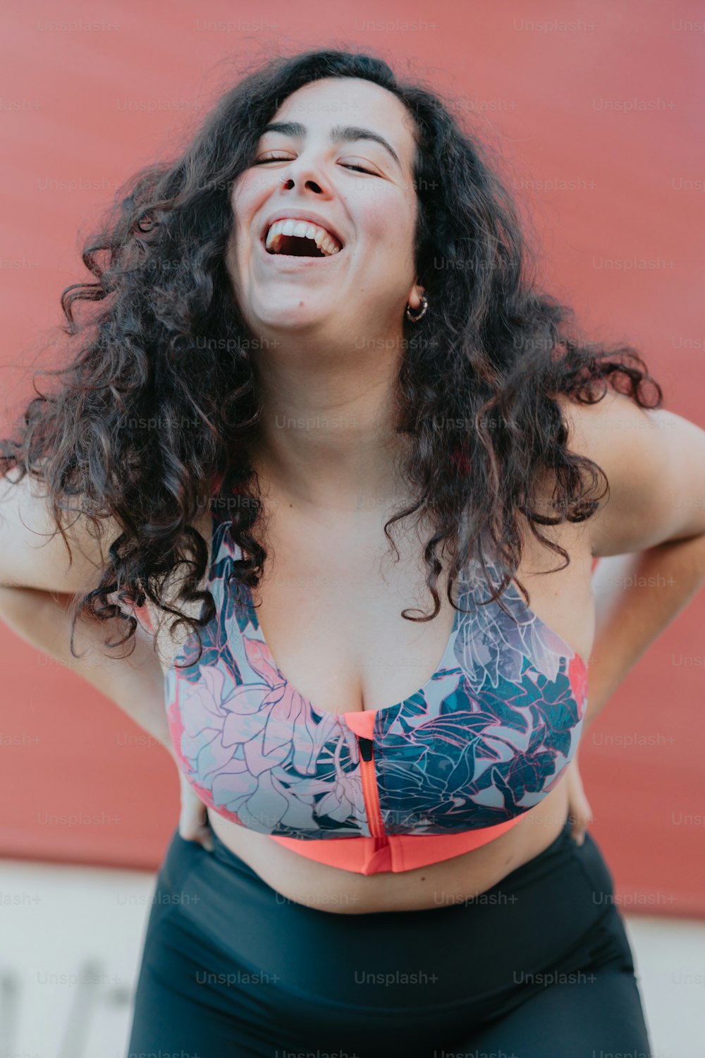 a woman in a bikini top laughing and holding her hands behind her back