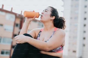 a woman sitting on the ground drinking from a cup