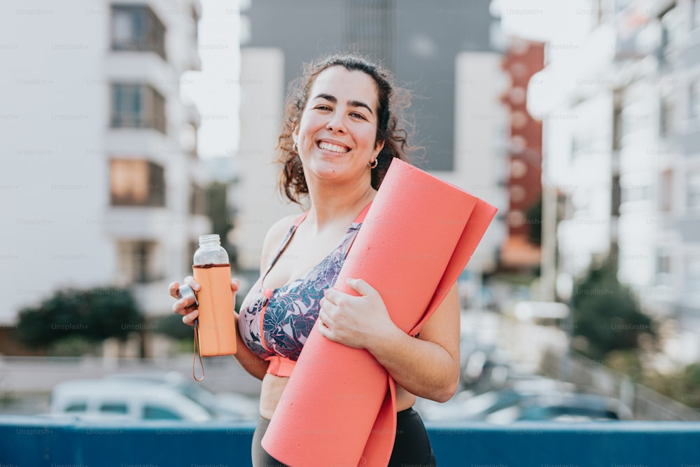 a woman holding a yoga mat and a bottle of water