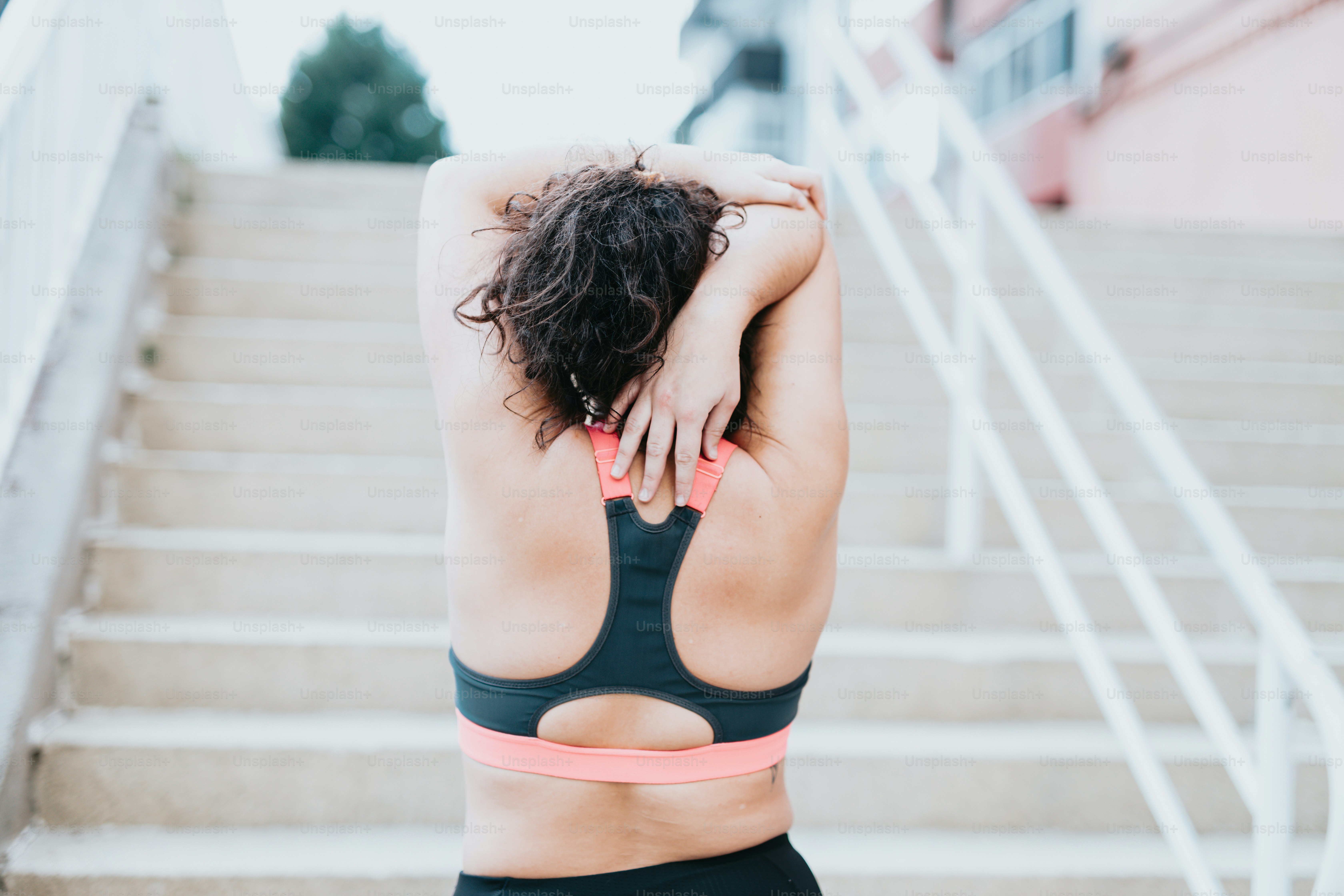 a woman in a sports bra top is standing on a set of stairs