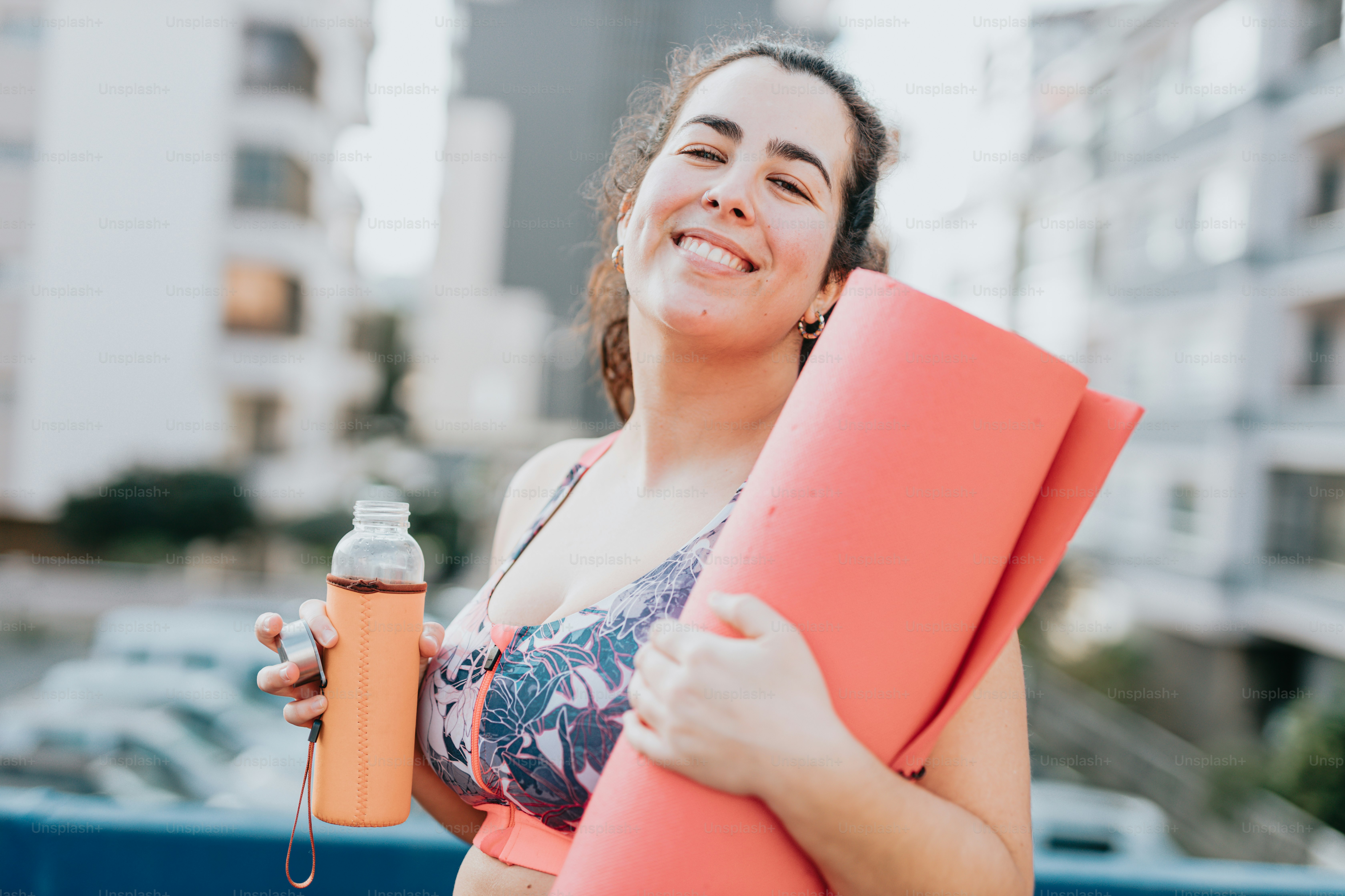 a woman holding a yoga mat and a bottle of water