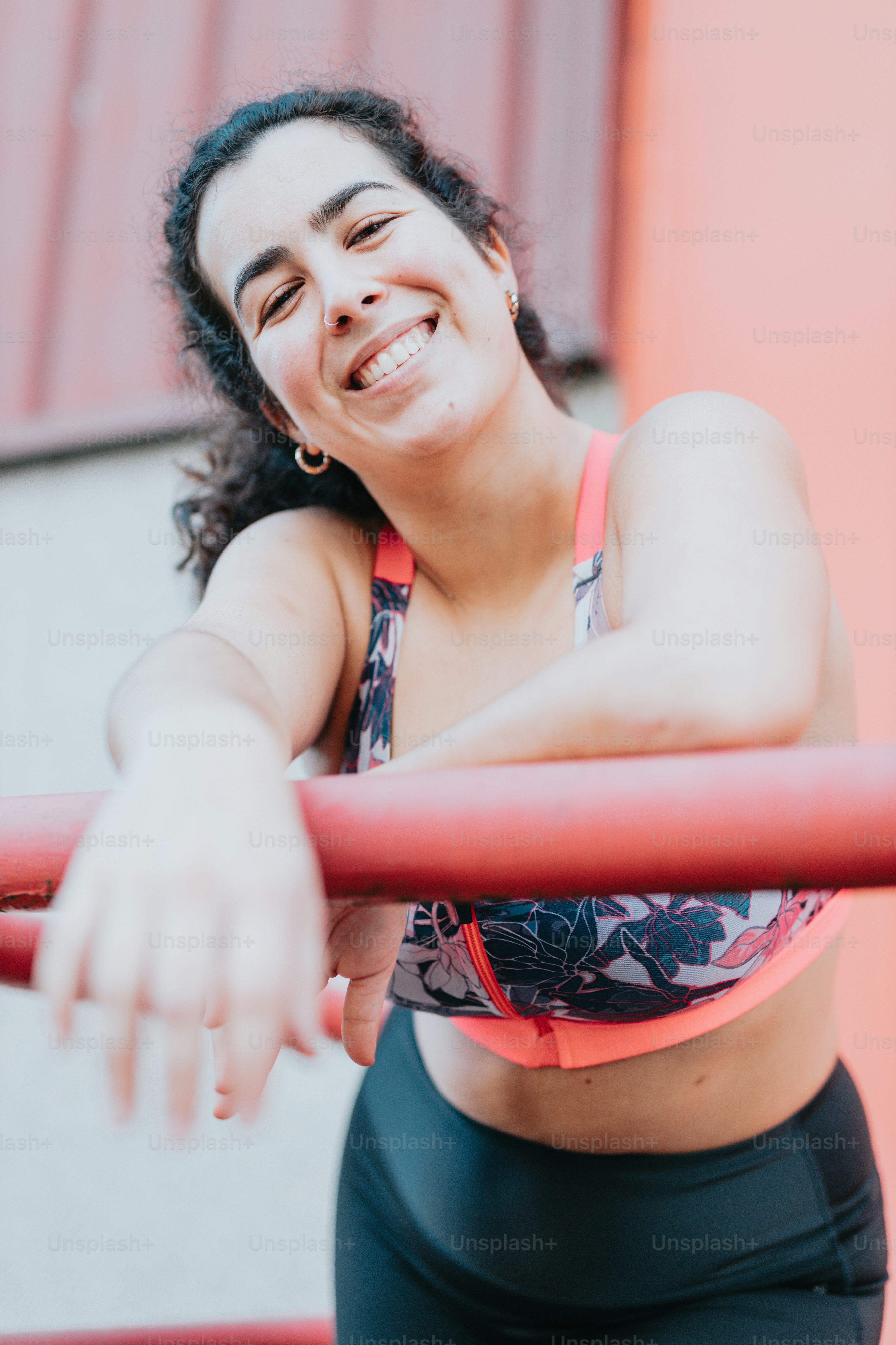 a woman in a sports bra top leaning on a pole