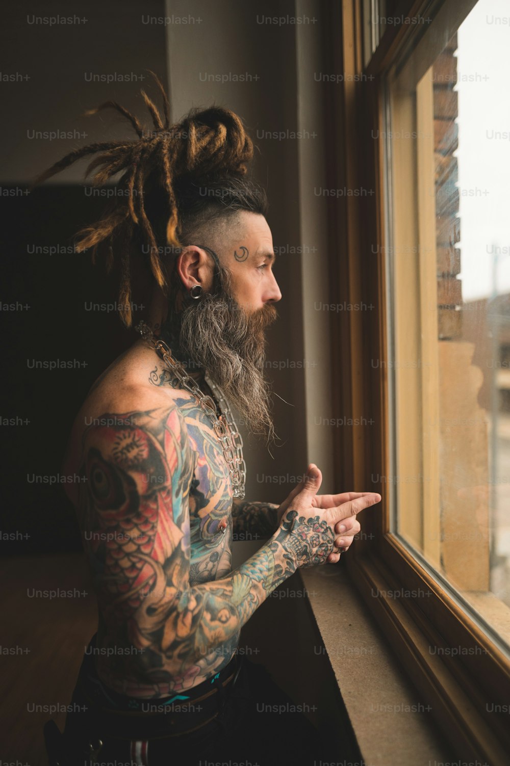 um homem com dreadlocks olhando para fora de uma janela