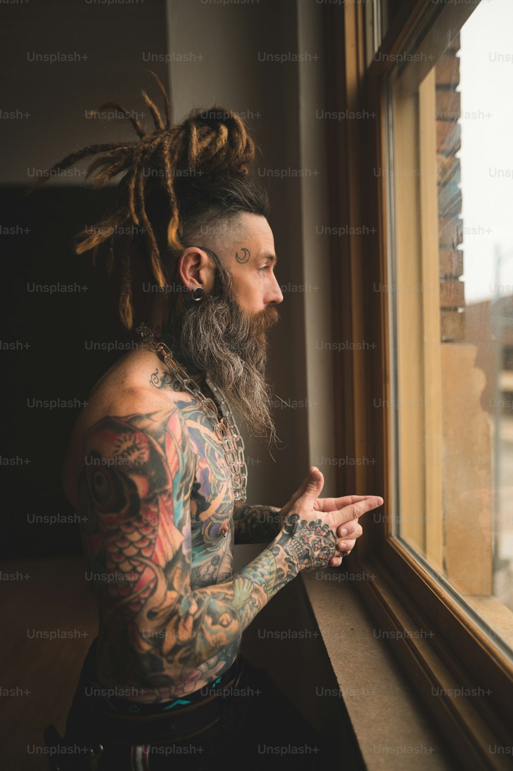 um homem com dreadlocks olhando para fora de uma janela