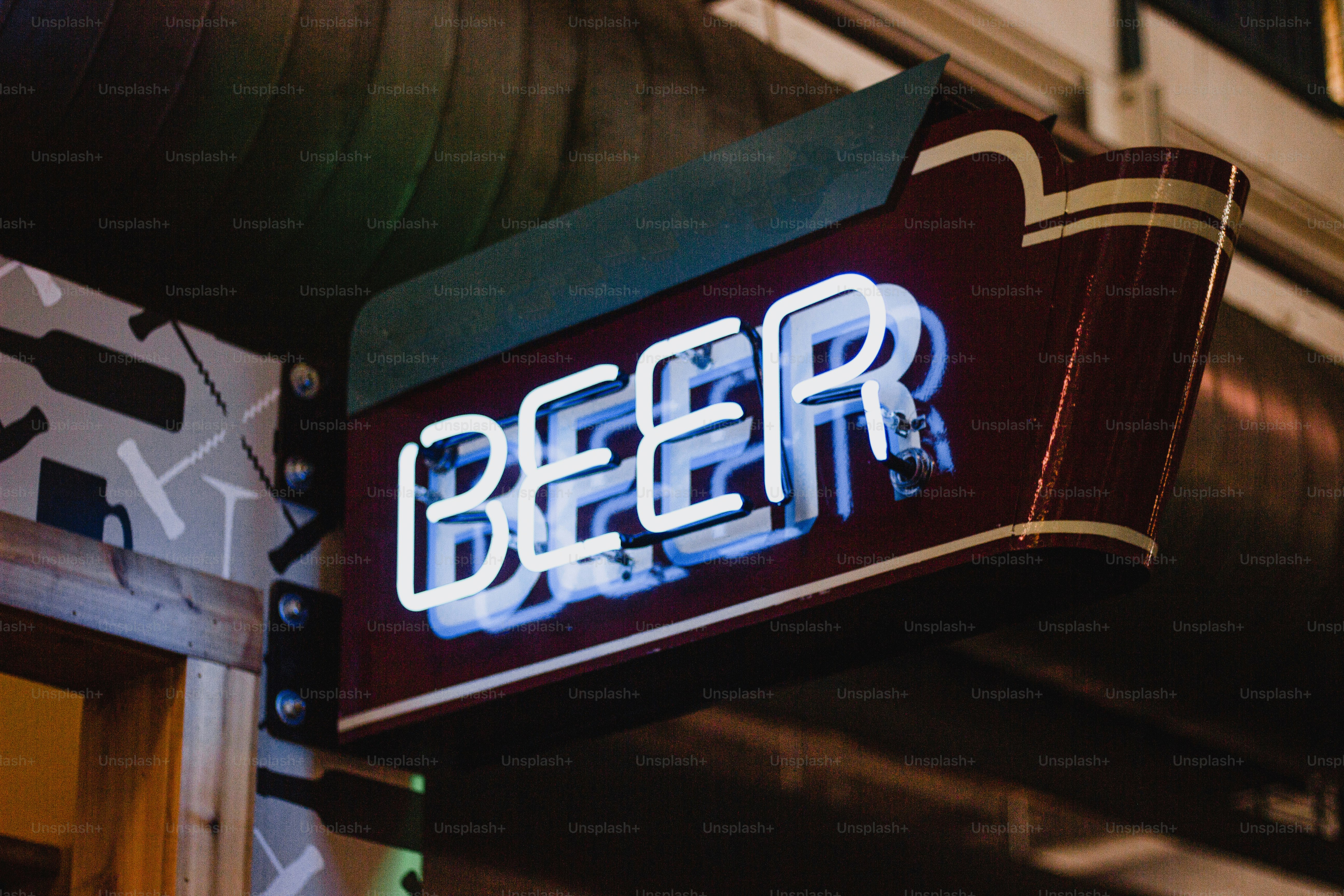 a neon sign that reads beer hangs from the side of a building