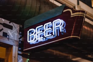 a neon sign that reads beer hangs from the side of a building