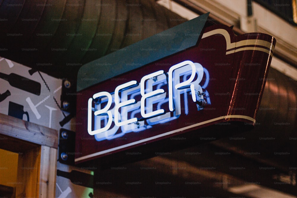 a neon sign that reads beer hangs from the side of a building