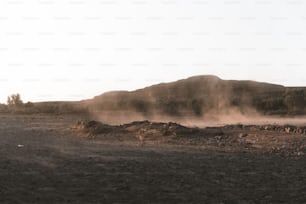 a dirt field with a mountain in the background