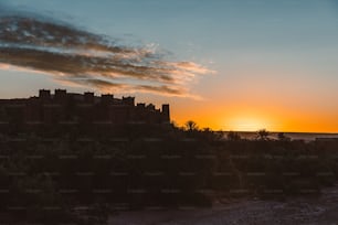 the sun is setting behind a castle on a hill