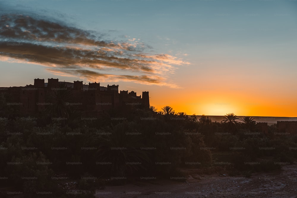 Le soleil se couche derrière un château sur une colline