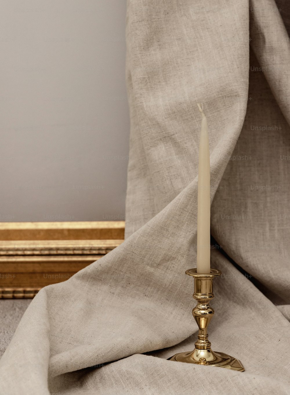 Una vela está sentada sobre una mesa junto a una cortina