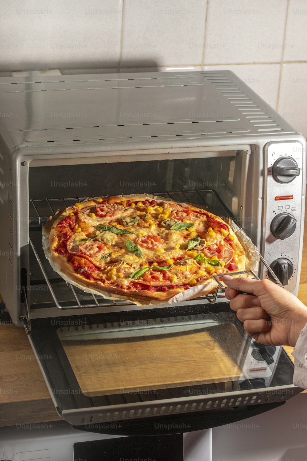 a person taking a pizza out of a toaster oven