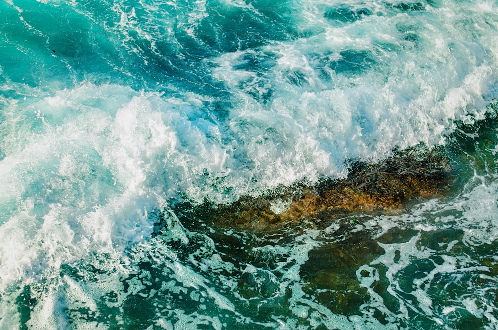 an aerial view of the ocean waves and rocks