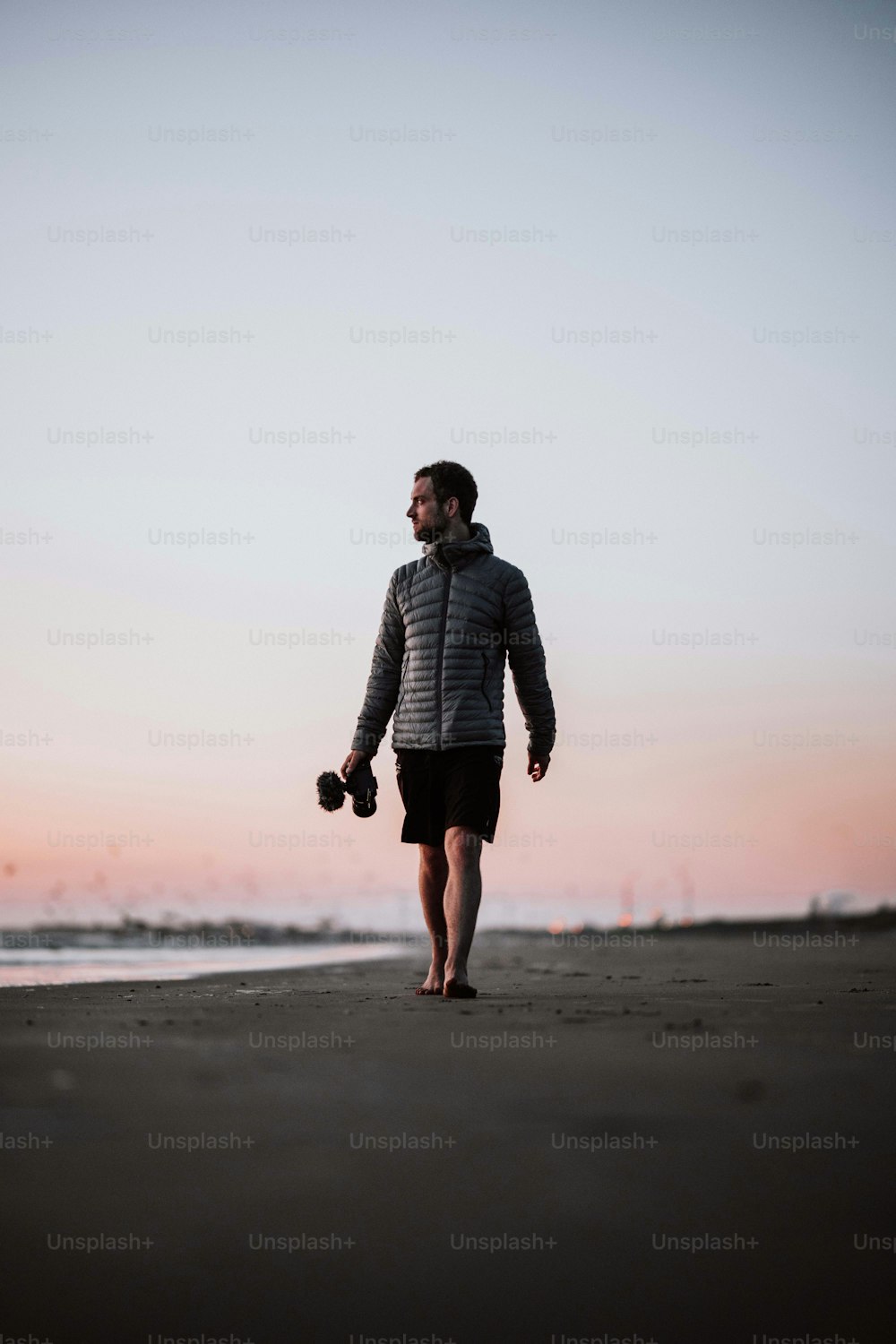 Un hombre caminando por una playa sosteniendo un par de tontos tontos tontos tontos tontos tontos tontos