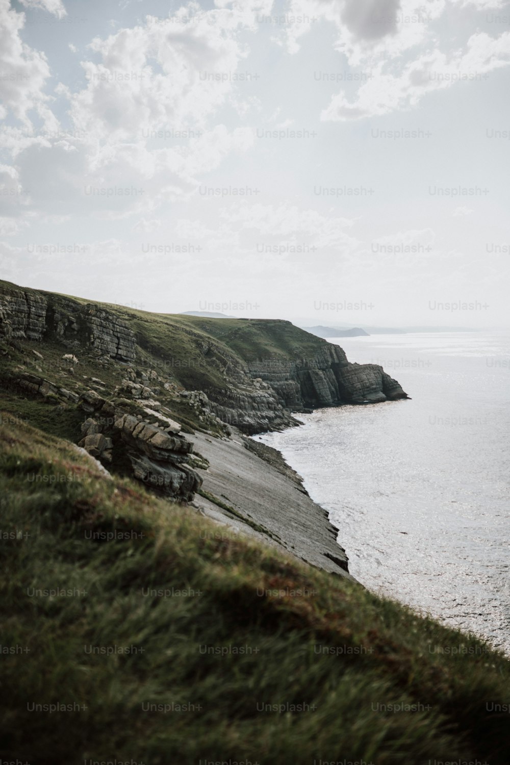 a grassy hill with a body of water in the background