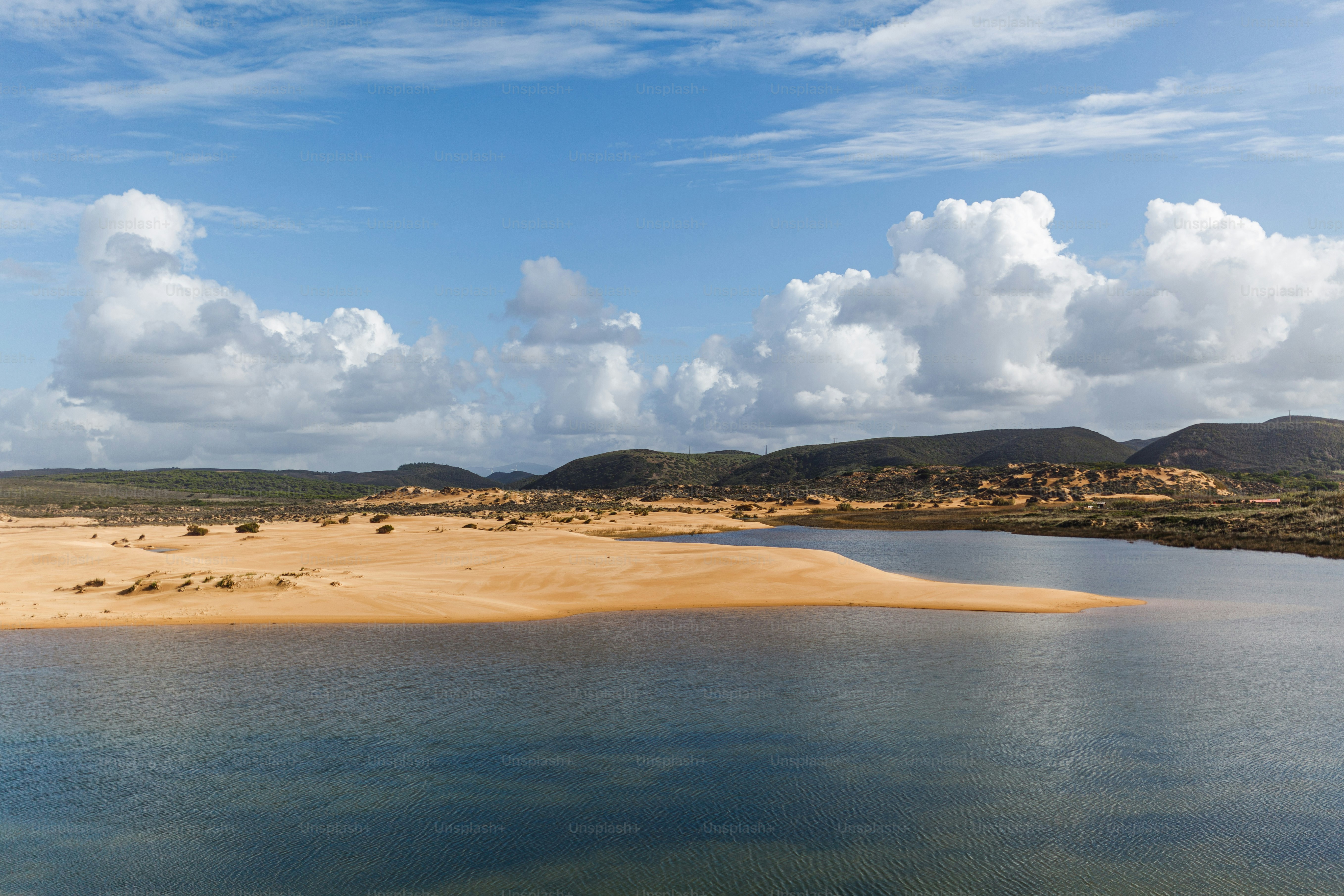 a body of water surrounded by hills and clouds