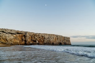 una spiaggia con onde che arrivano a riva e una roccia affiorante
