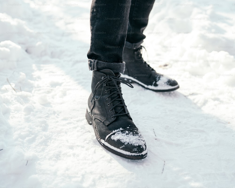 a person standing in the snow wearing a pair of black shoes