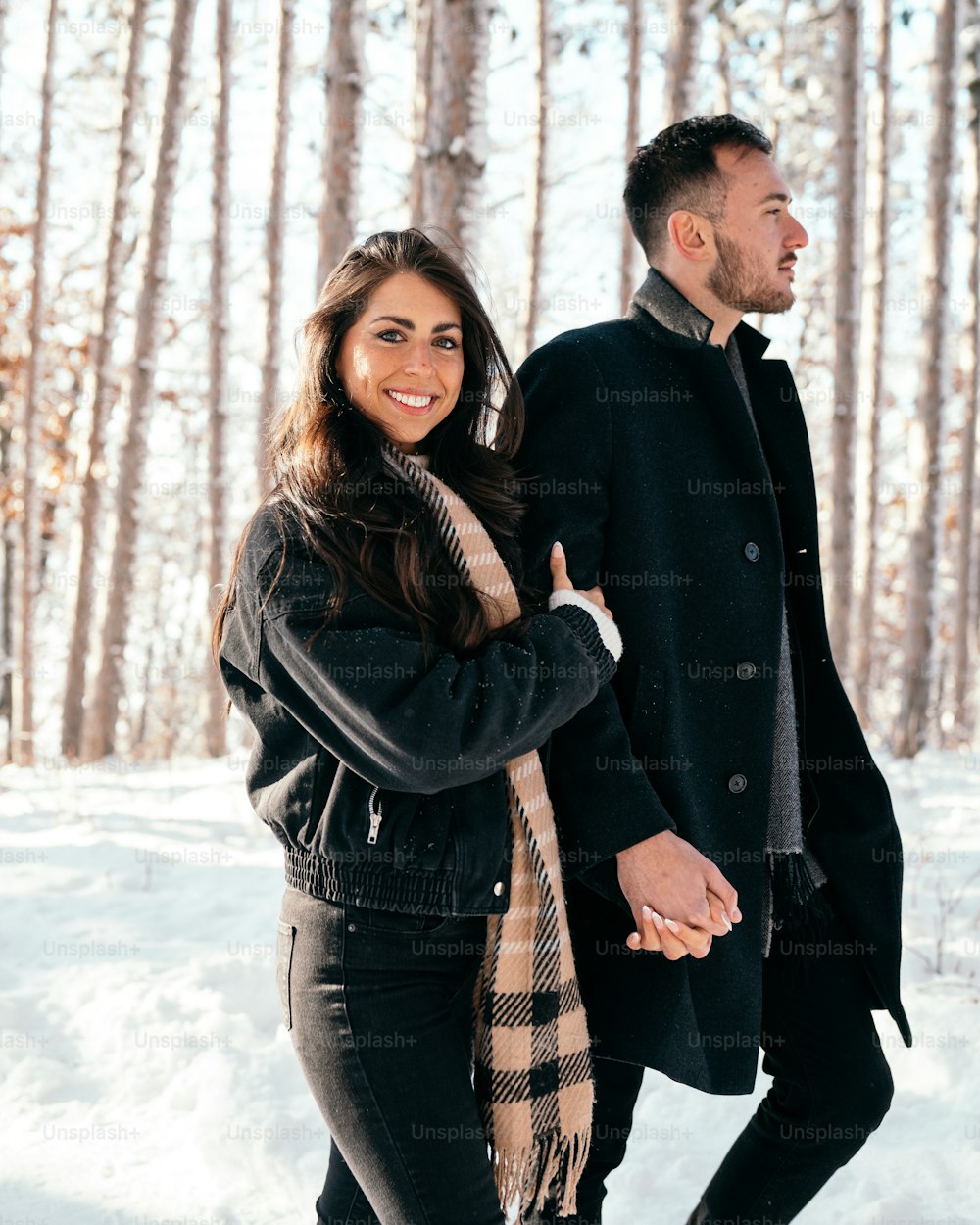 a man and a woman holding hands in the snow