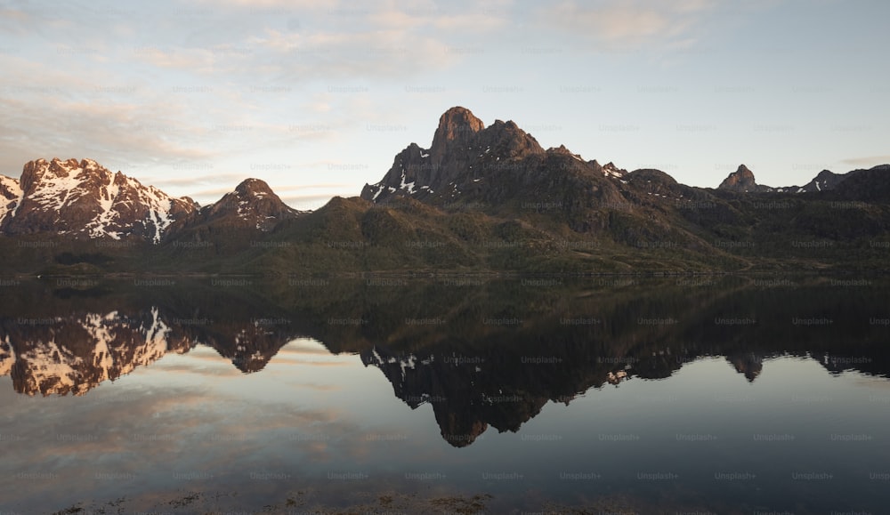 a mountain range is reflected in the still water of a lake