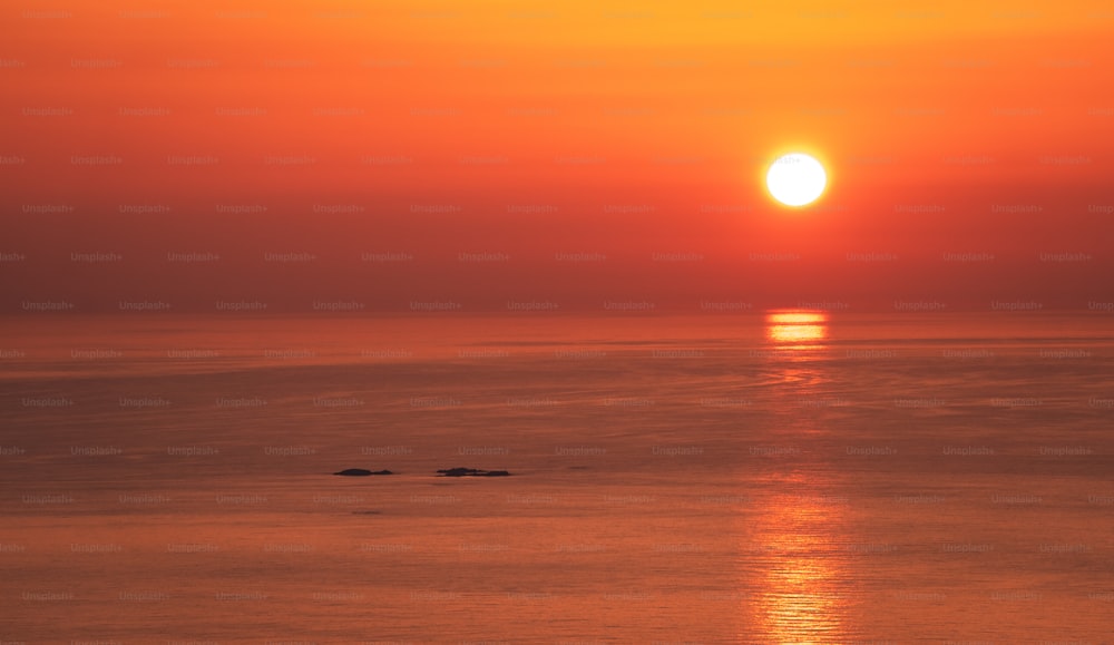 una gran masa de agua con una puesta de sol en el fondo