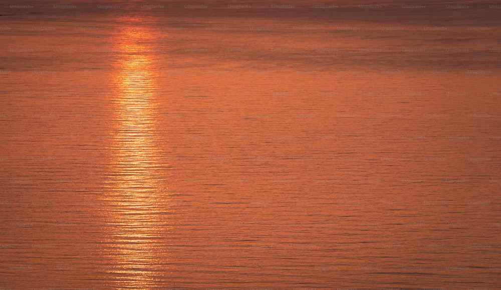 El sol se está poniendo sobre el océano con un bote en el agua