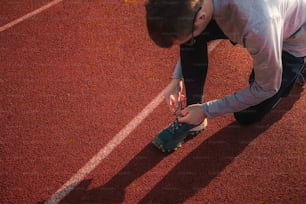 a man tying a pair of shoes on a tennis court