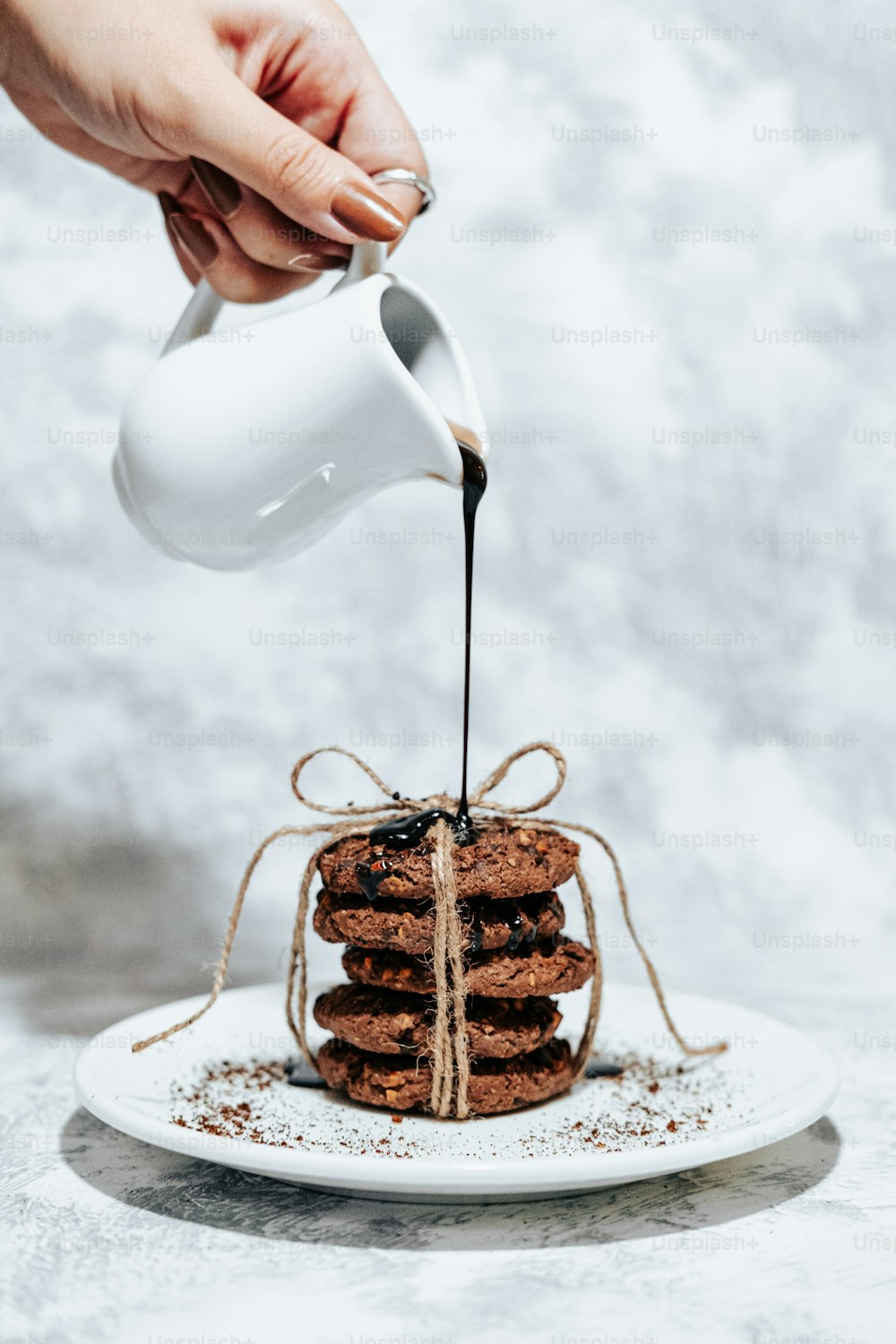 a person pouring syrup on a stack of cookies
