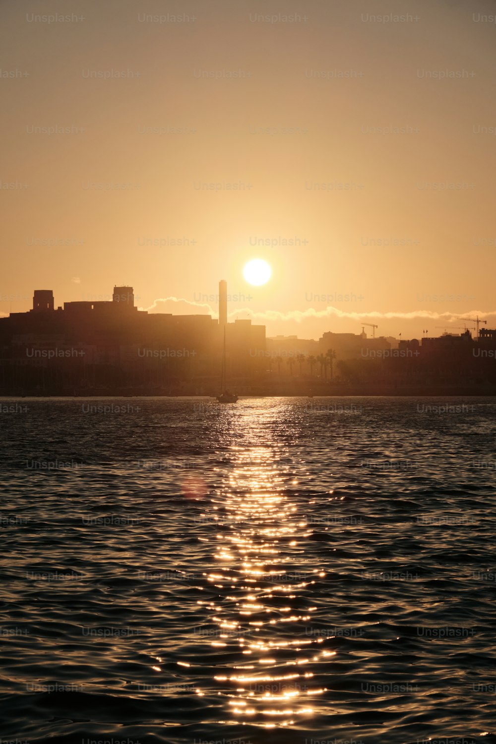 the sun is setting over the water in the city