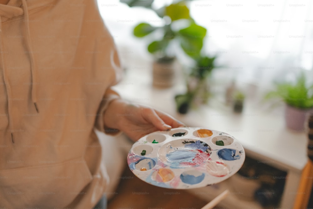 une personne tenant une palette de peinture dans sa main