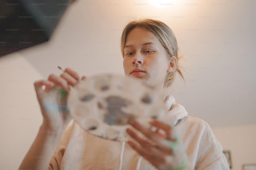 uma mulher segurando um objeto branco em suas mãos