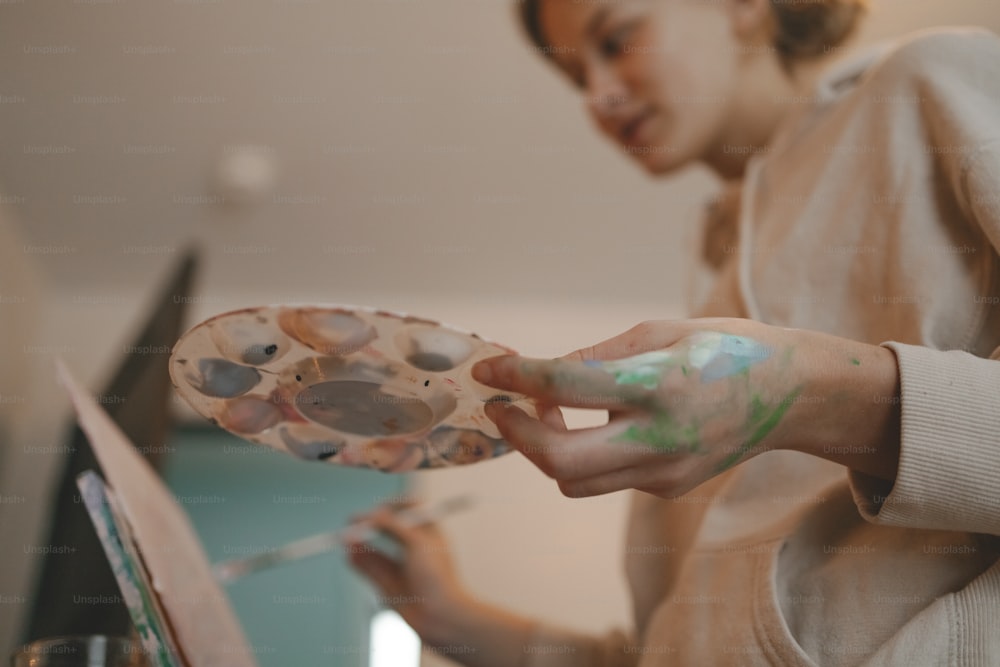 a woman is holding a paintbrush and a palette
