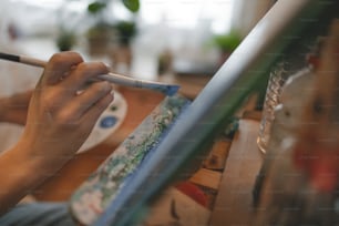 a person holding a brush and painting on a canvas