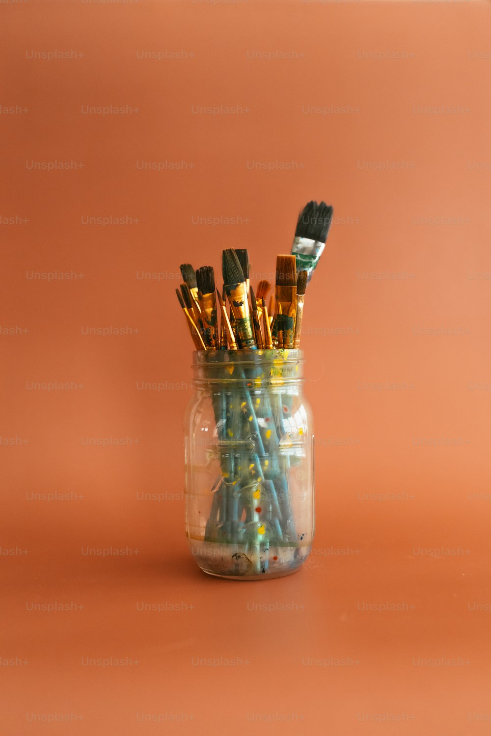 a jar filled with lots of paint brushes