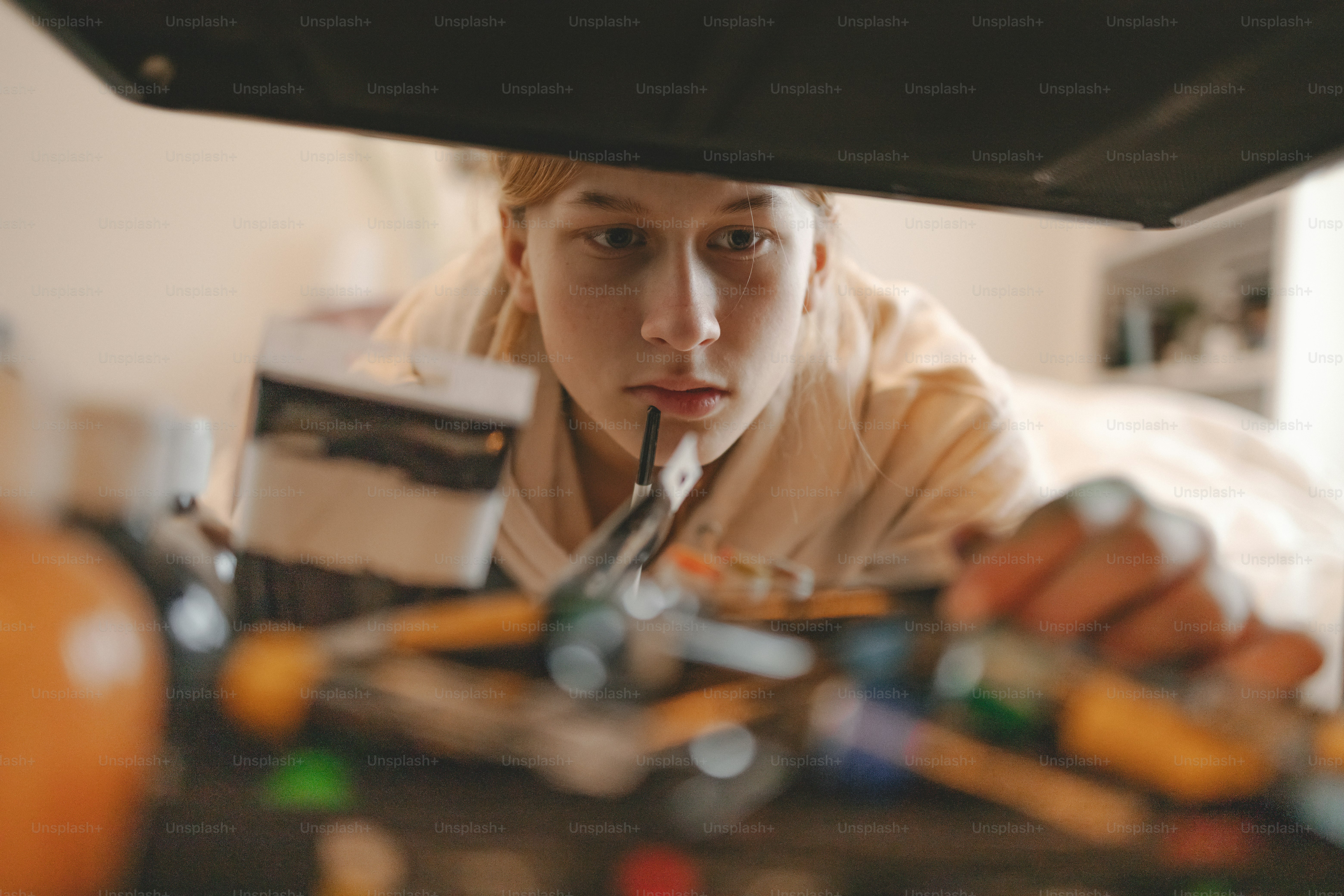여자가 자동차 후드 아래에서 장난감 자동차를보고 있다