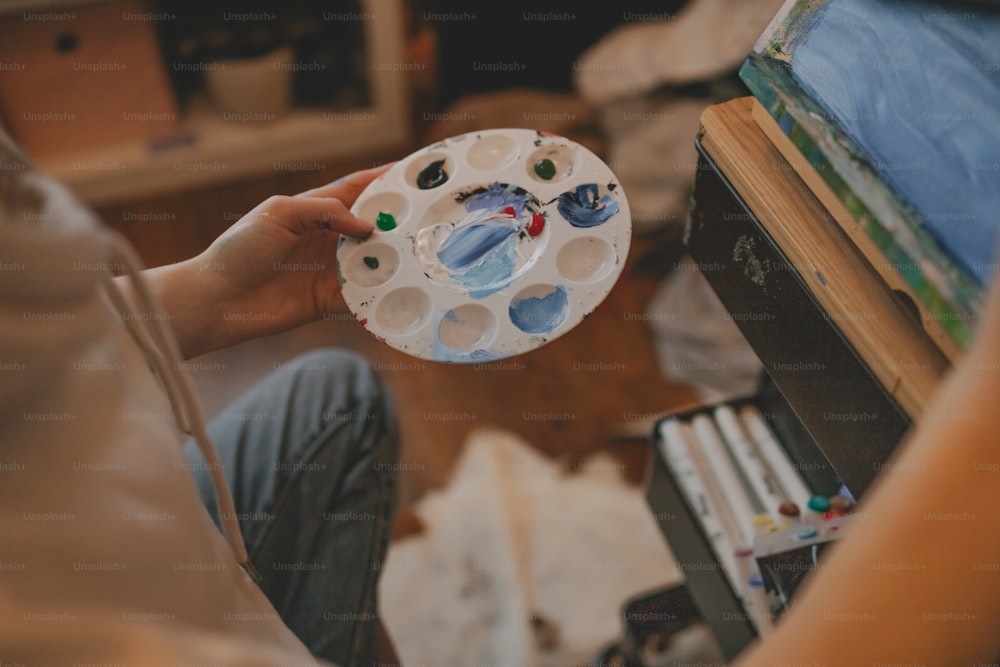 a person holding a paper plate with paint on it