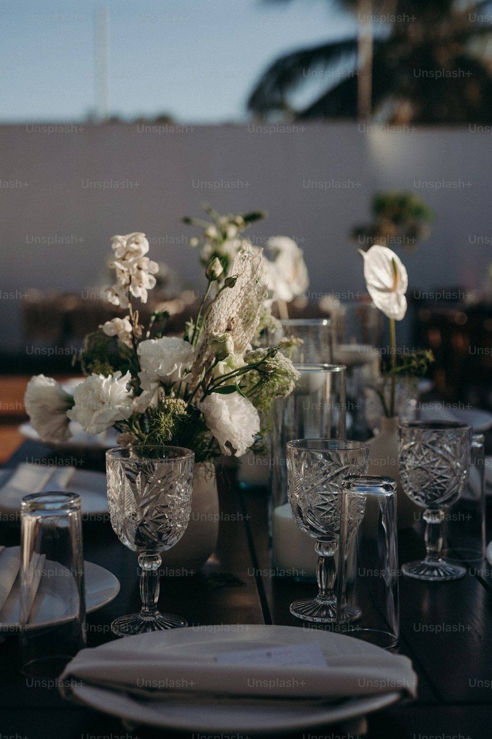 a table set for a formal dinner with flowers in vases