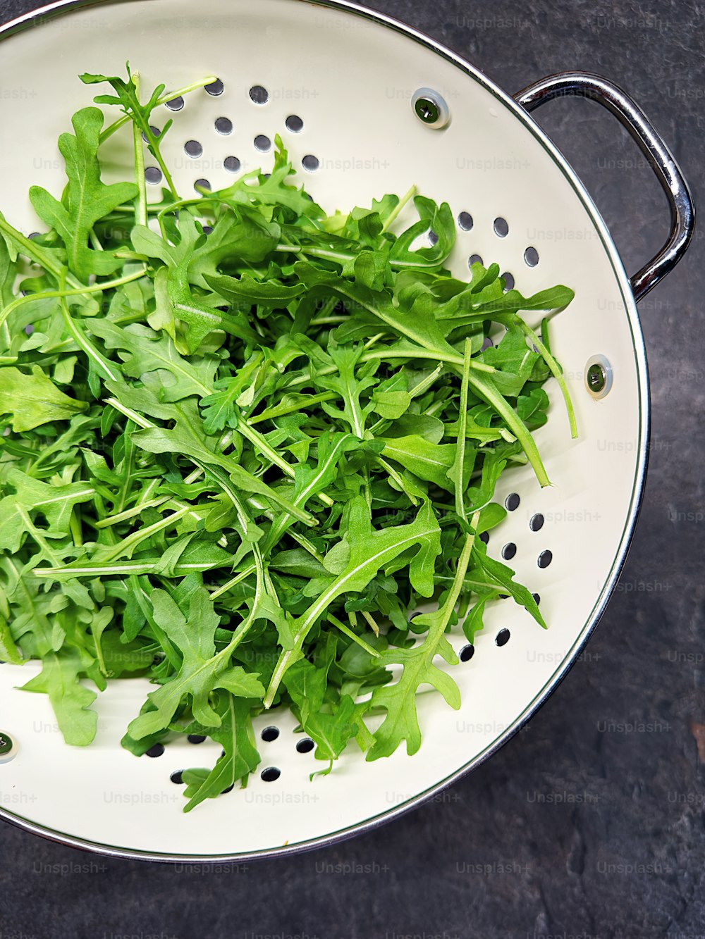 a bunch of green leafy greens in a colander