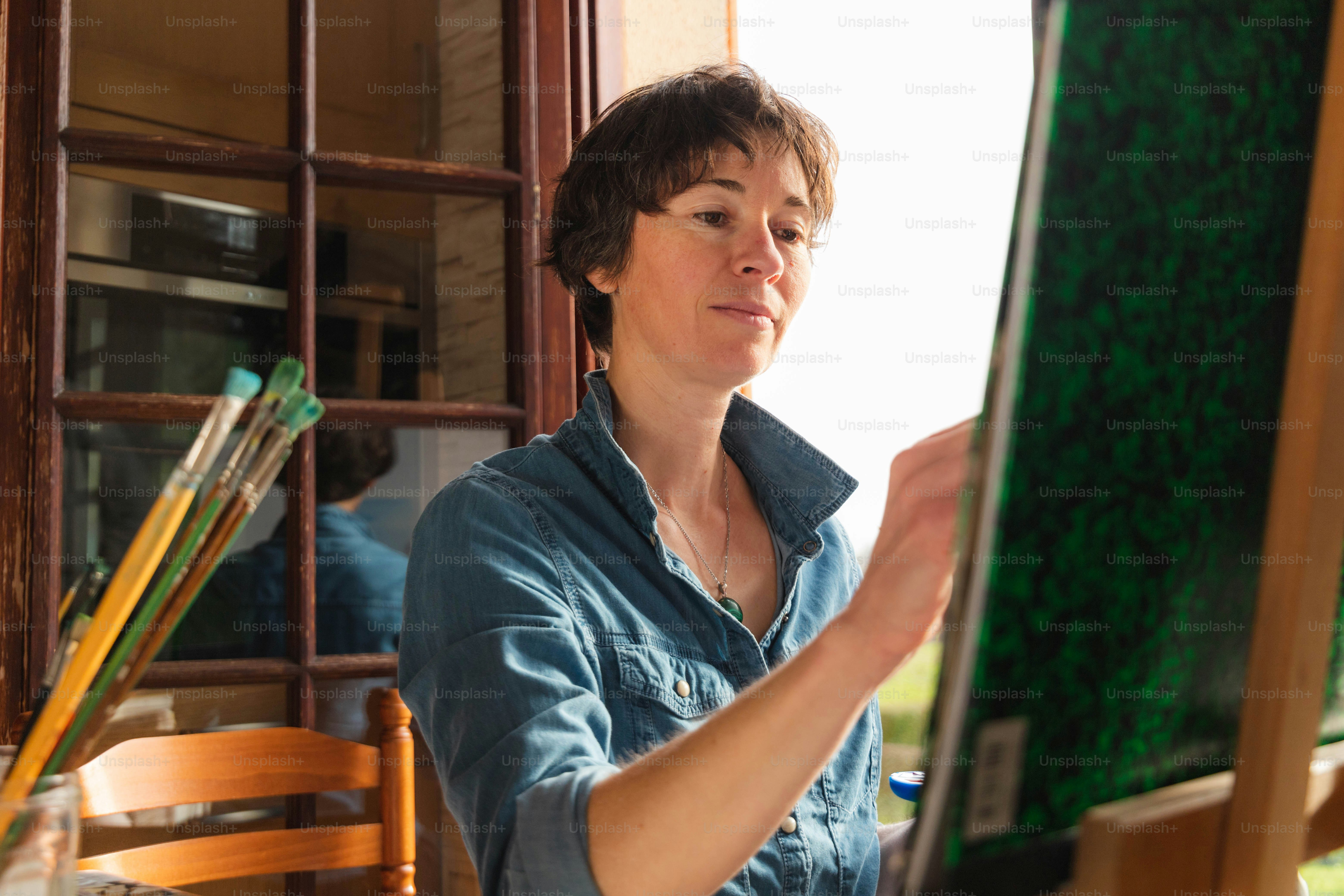 a woman sitting at a table with a painting