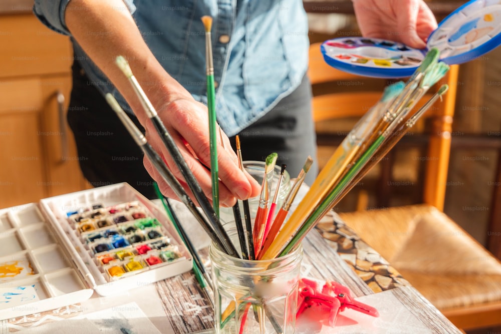a person is painting on a table with paintbrushes