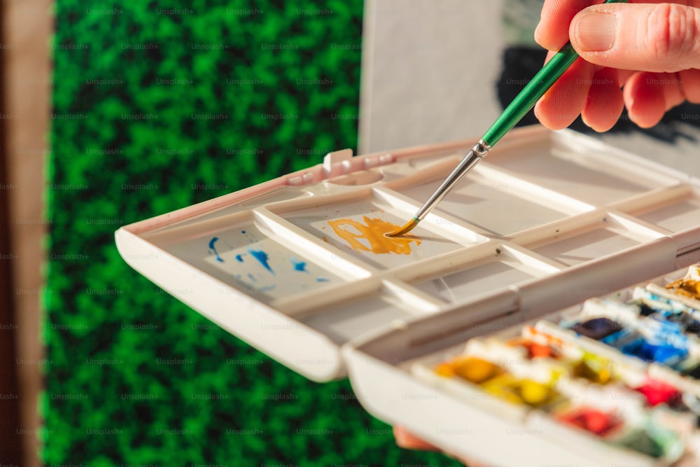 a person holding a paintbrush in a tray of paint