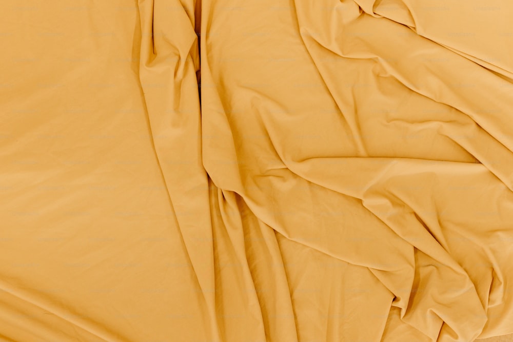 a close up of a bed with yellow sheets