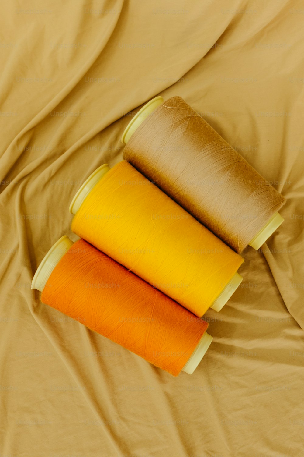 three rolls of yellow and orange fabric on a bed