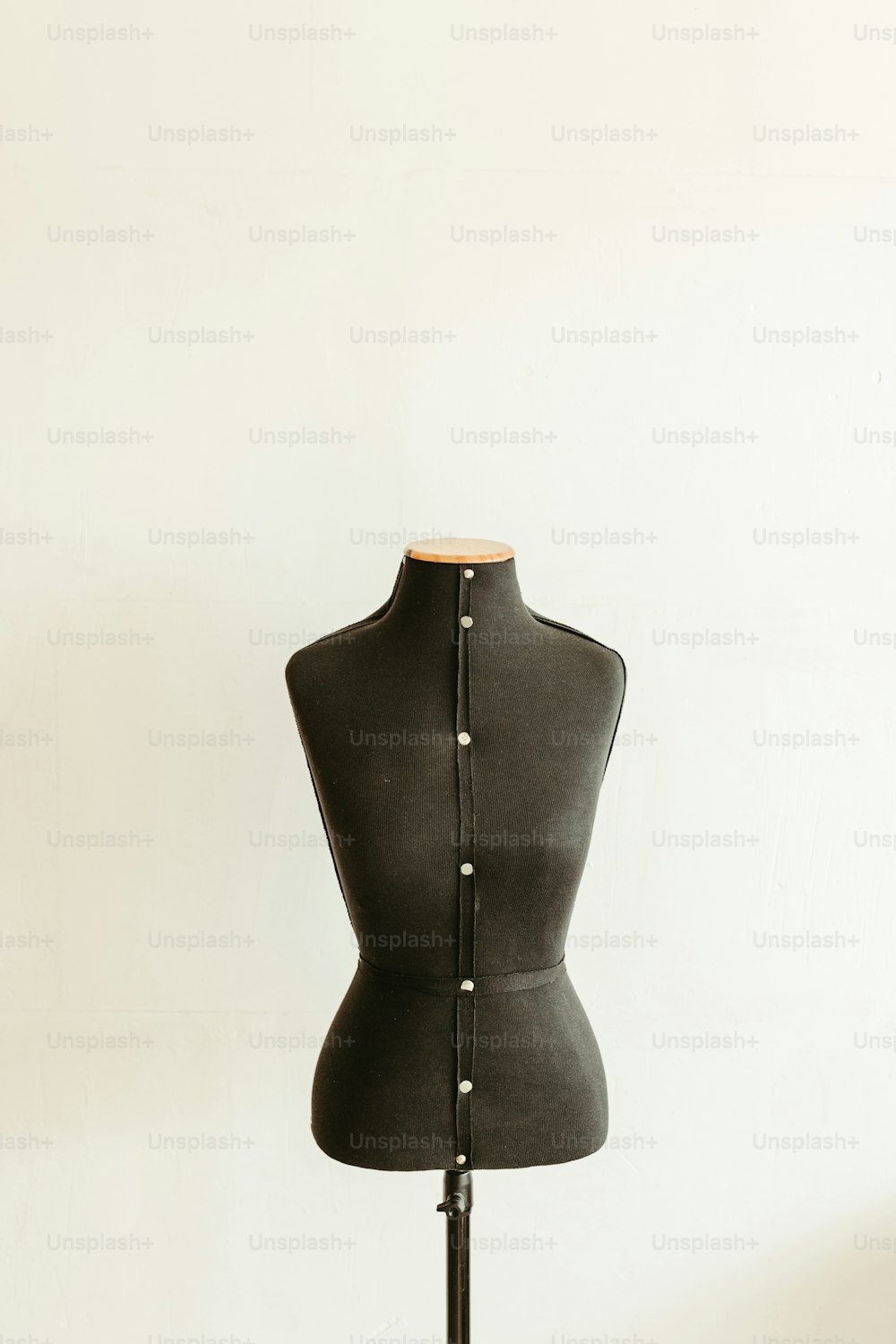 a black mannequin on a stand with a white wall in the background