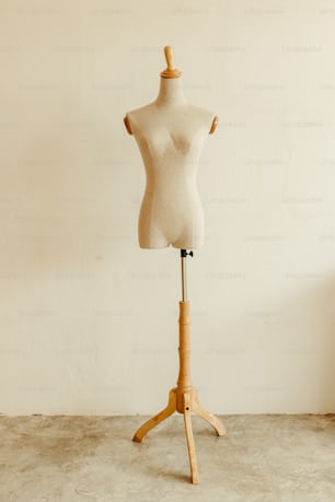 a mannequin on a wooden stand in front of a wall