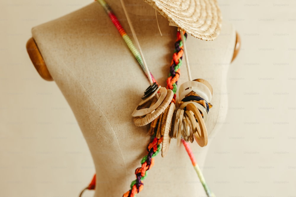 a mannequin wearing a straw hat and colorful necklace