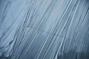Un homme grimpe sur le flanc d’un bâtiment recouvert de plastique