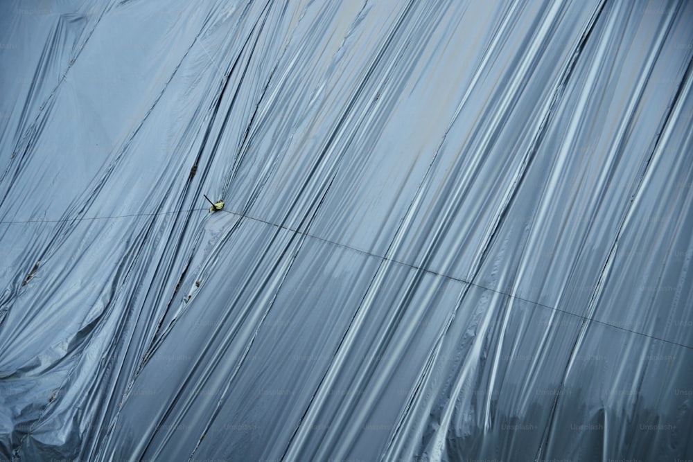 Un hombre trepando por el costado de un edificio cubierto de plástico
